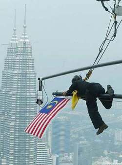 Afbeelding: Stunt director van het Zuid-Afikaanse produktiehuis Francois Grobelaan vervangt een Fear Factor vlag met de Jalur Gemilang, de nationale vlag van Maleisië, op de KL Tower.