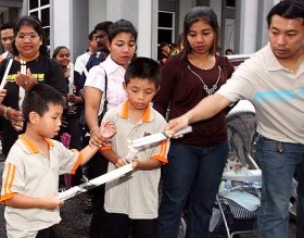Picture: Helping hand: A senior parishioner helping young ones light candles before joining in the procession